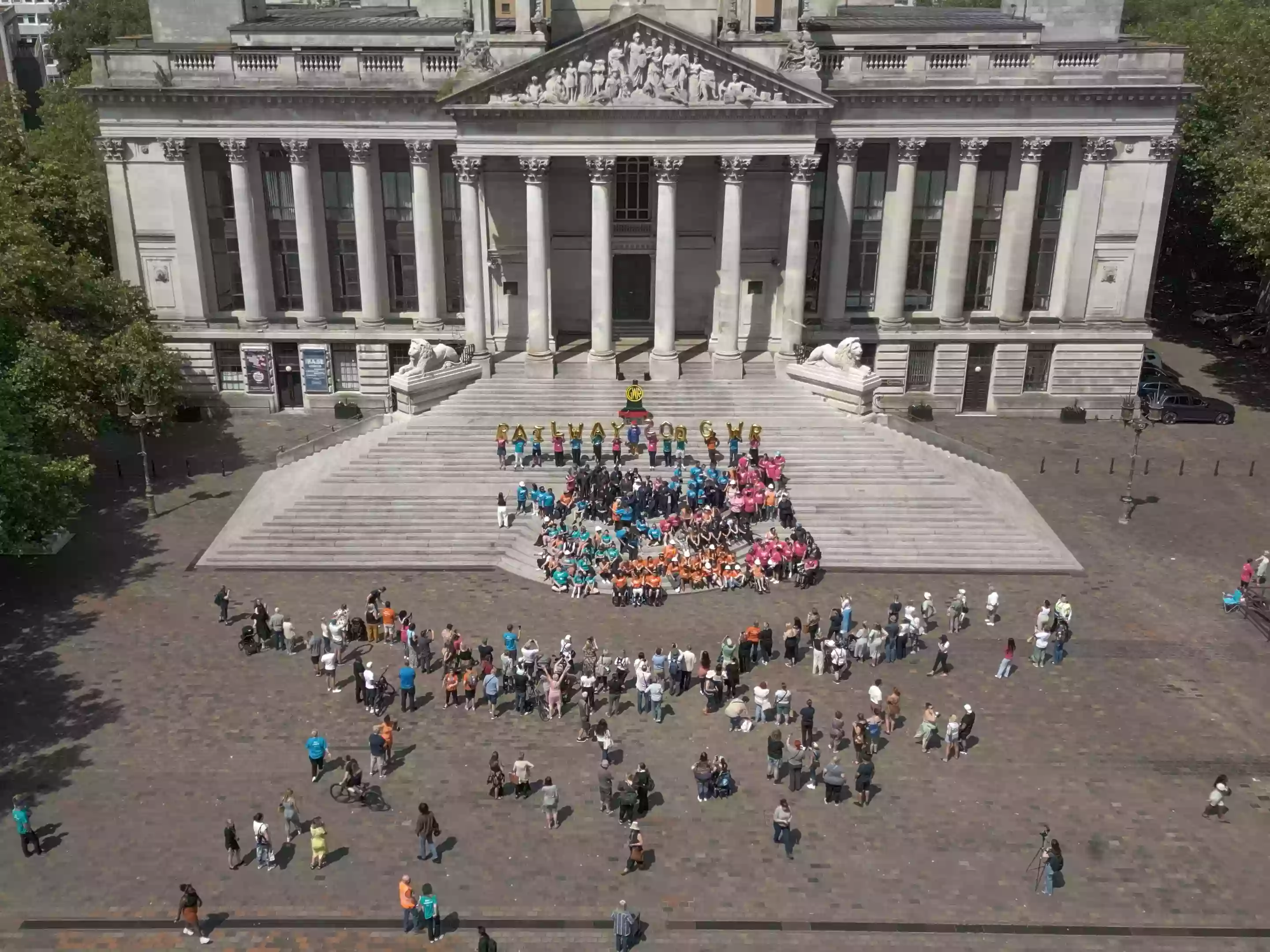 Aerial drone shot looking down at over 100 performers gathered in Guildhall Square, Portsmouth, during the Railway 200 community flashmob celebration