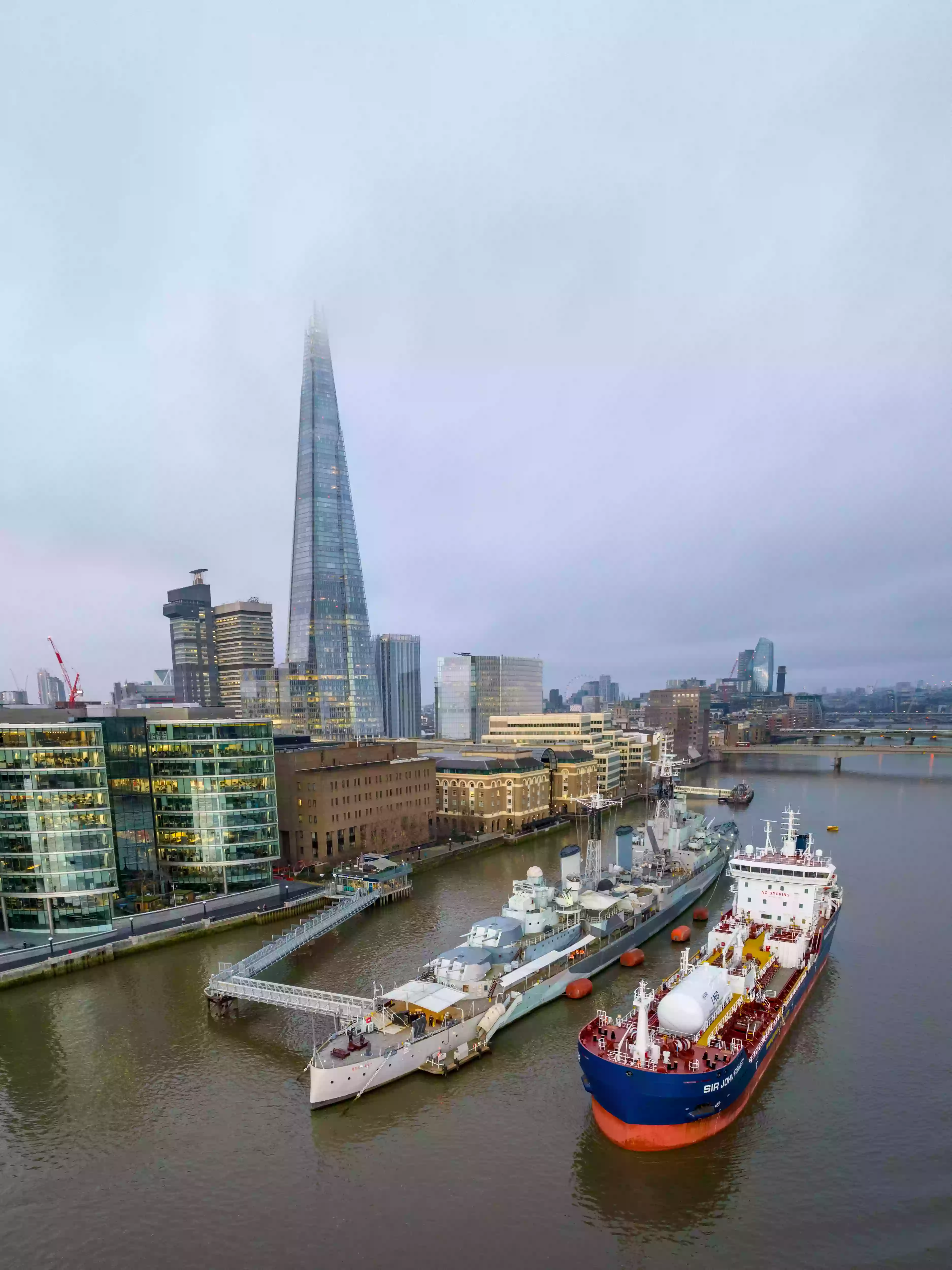 Aerial drone shot of the Sir John Fisher tanker moored in the Pool of London with the Shard in the background