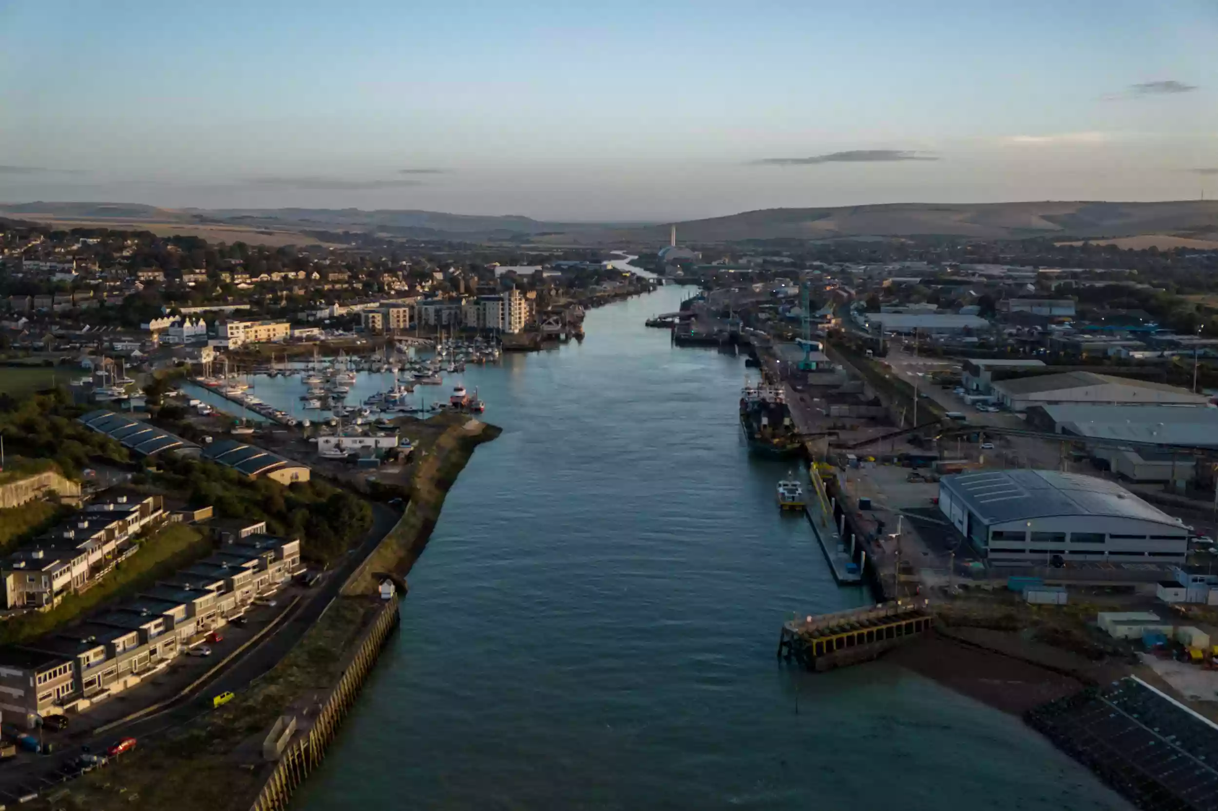 Wide aerial drone view of Newhaven harbour at dusk, with the Britannia Beaver and surrounding port operations laid out below.