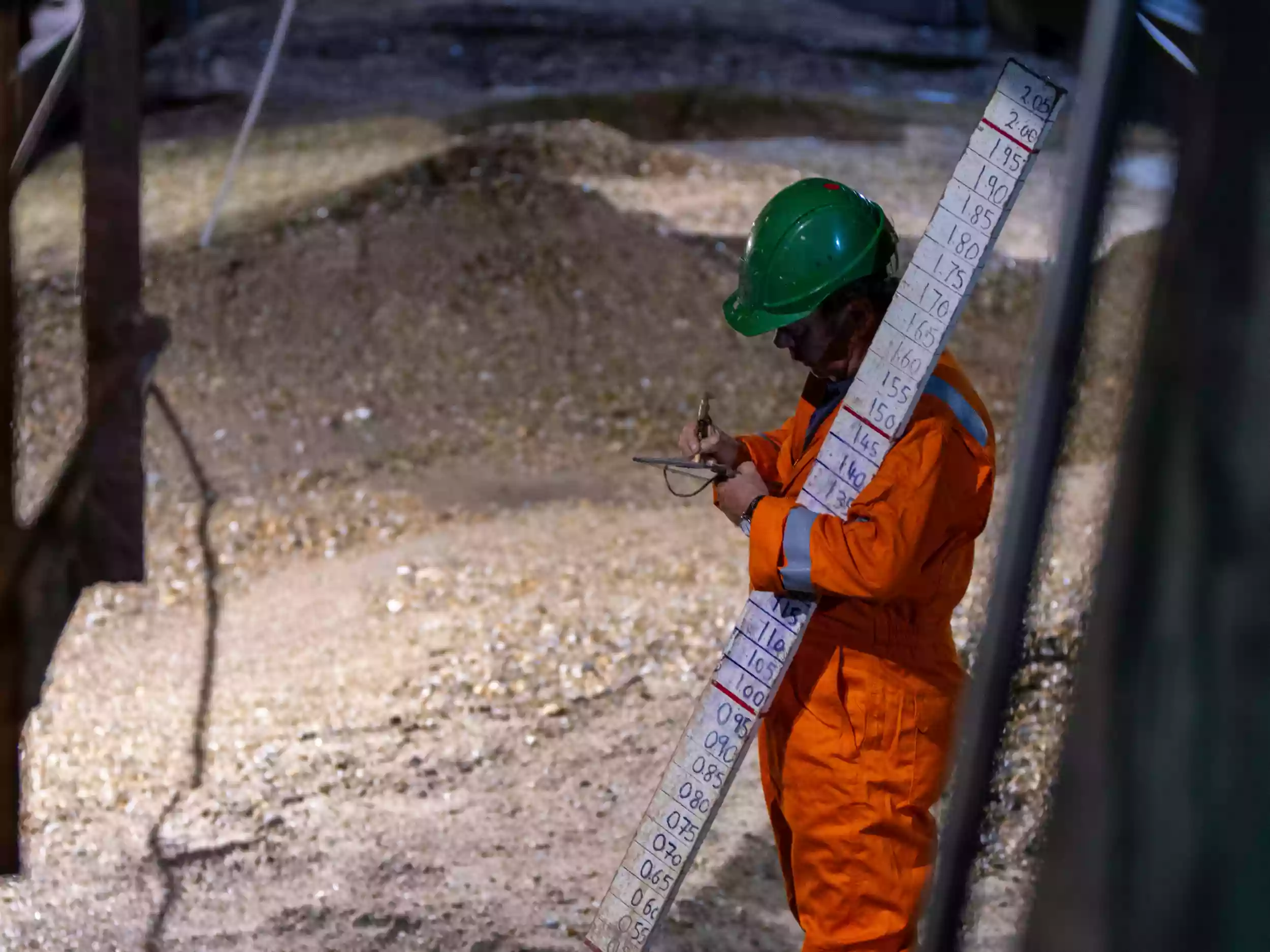 Crew member in orange hi-vis workwear standing on the deck of the Britannia Beaver alongside freshly loaded dredge material.