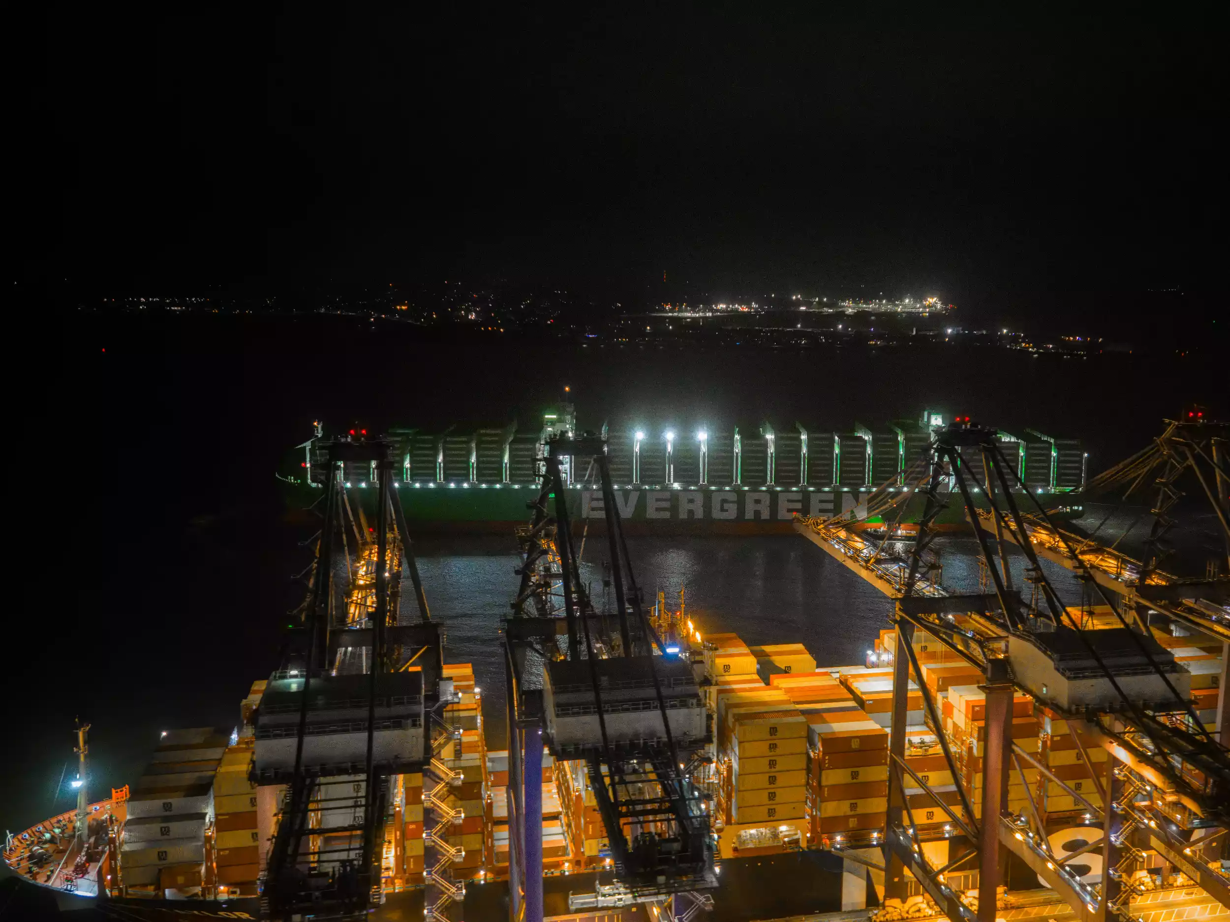 Overhead drone shot of Ever Eco illuminated at night alongside Felixstowe container terminal
