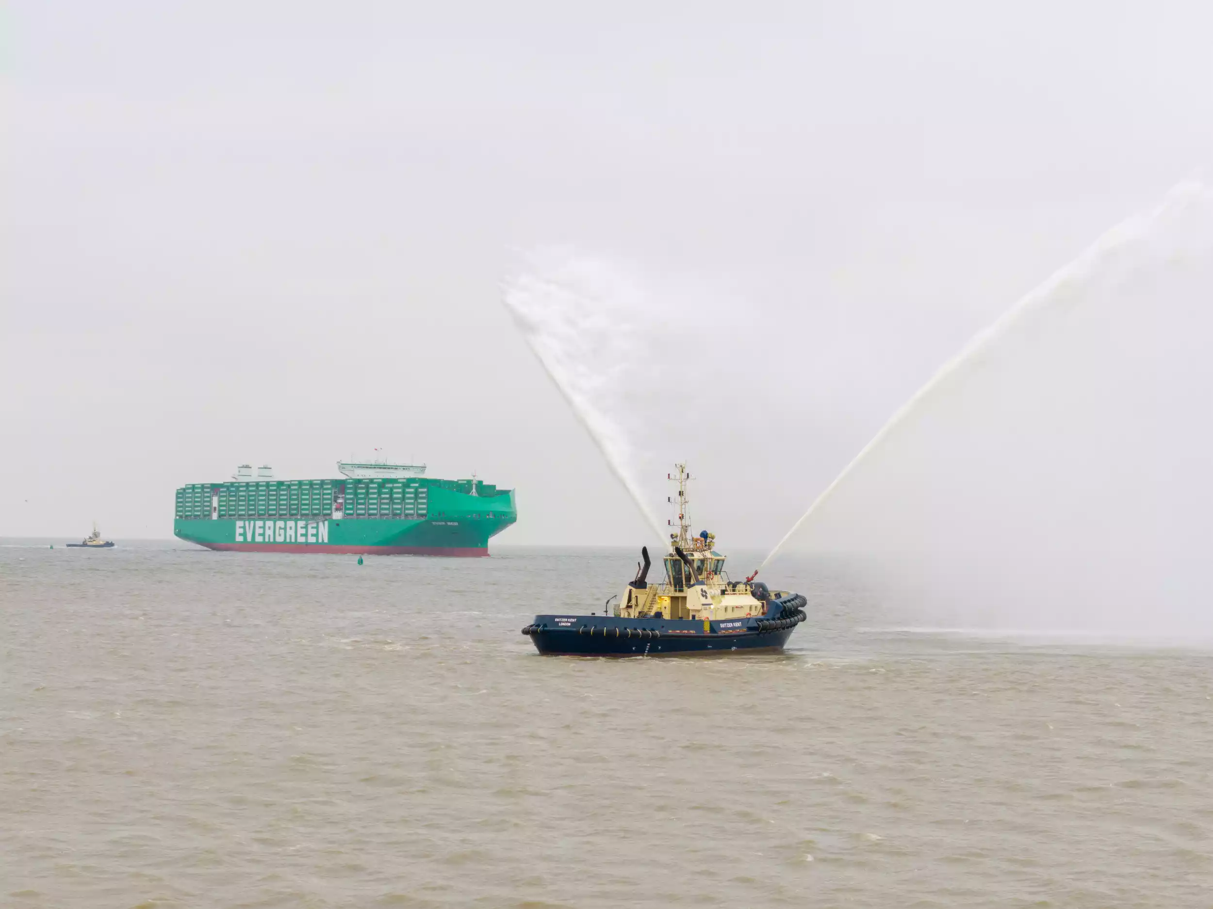 Wide aerial shot of Ever Eco being escorted by tugboats on arrival at Felixstowe