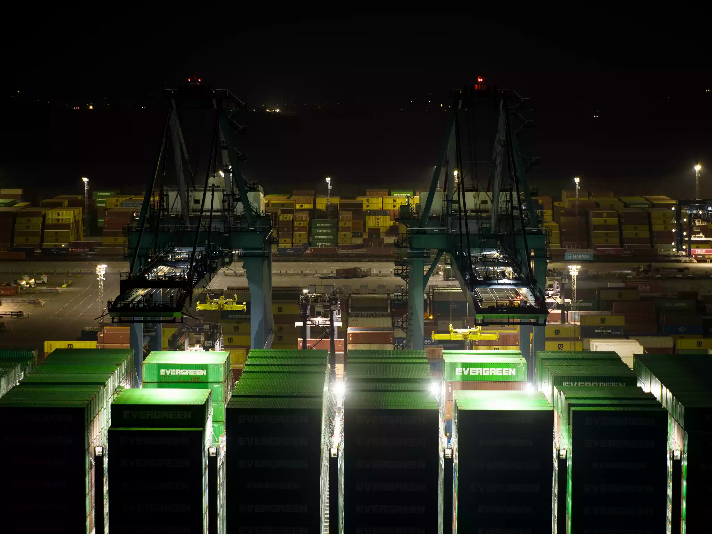 Aerial view of Ever Eco moored at Felixstowe terminal at night with cranes illuminated