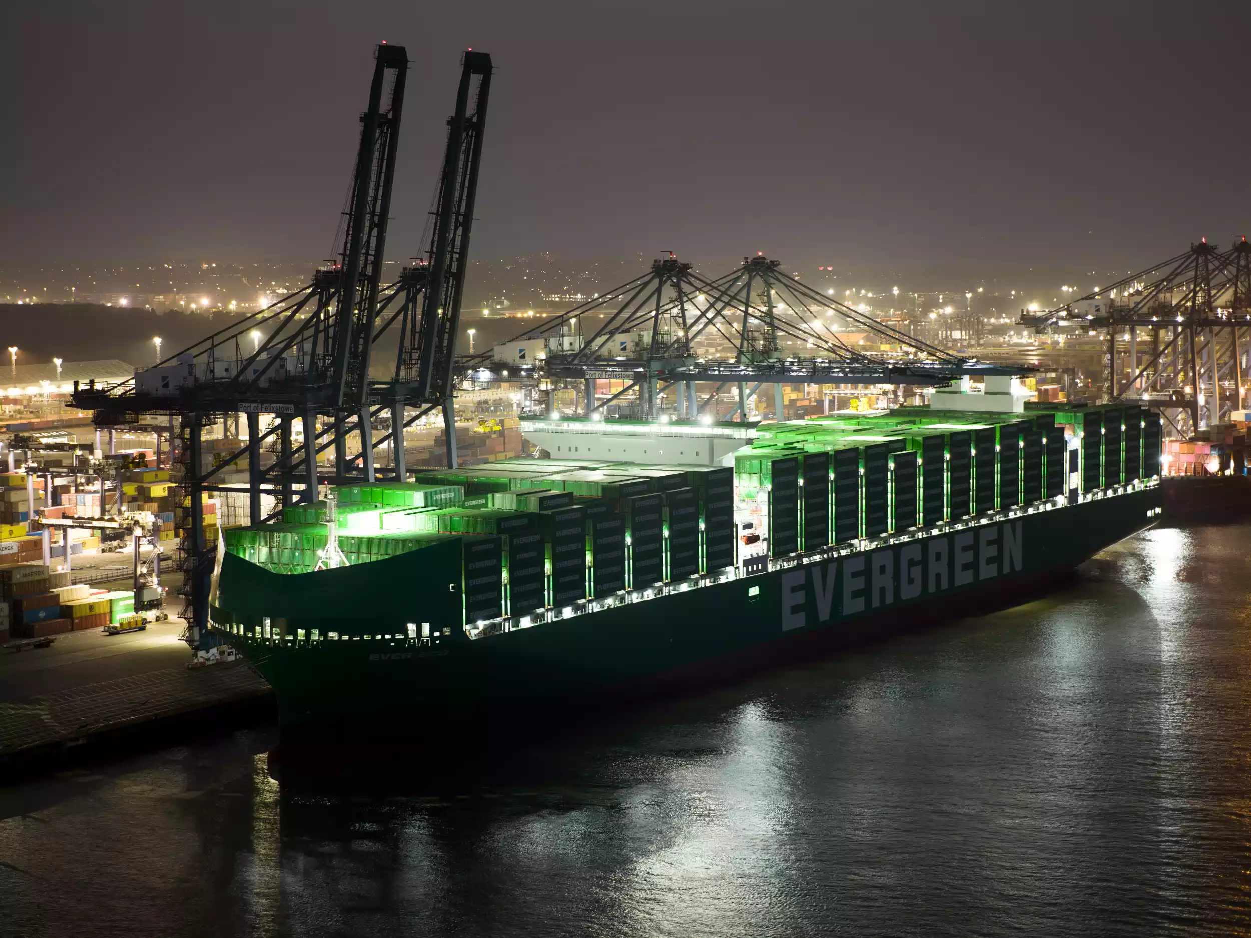 Wide night aerial of Ever Eco and Felixstowe container terminal lit up after dark