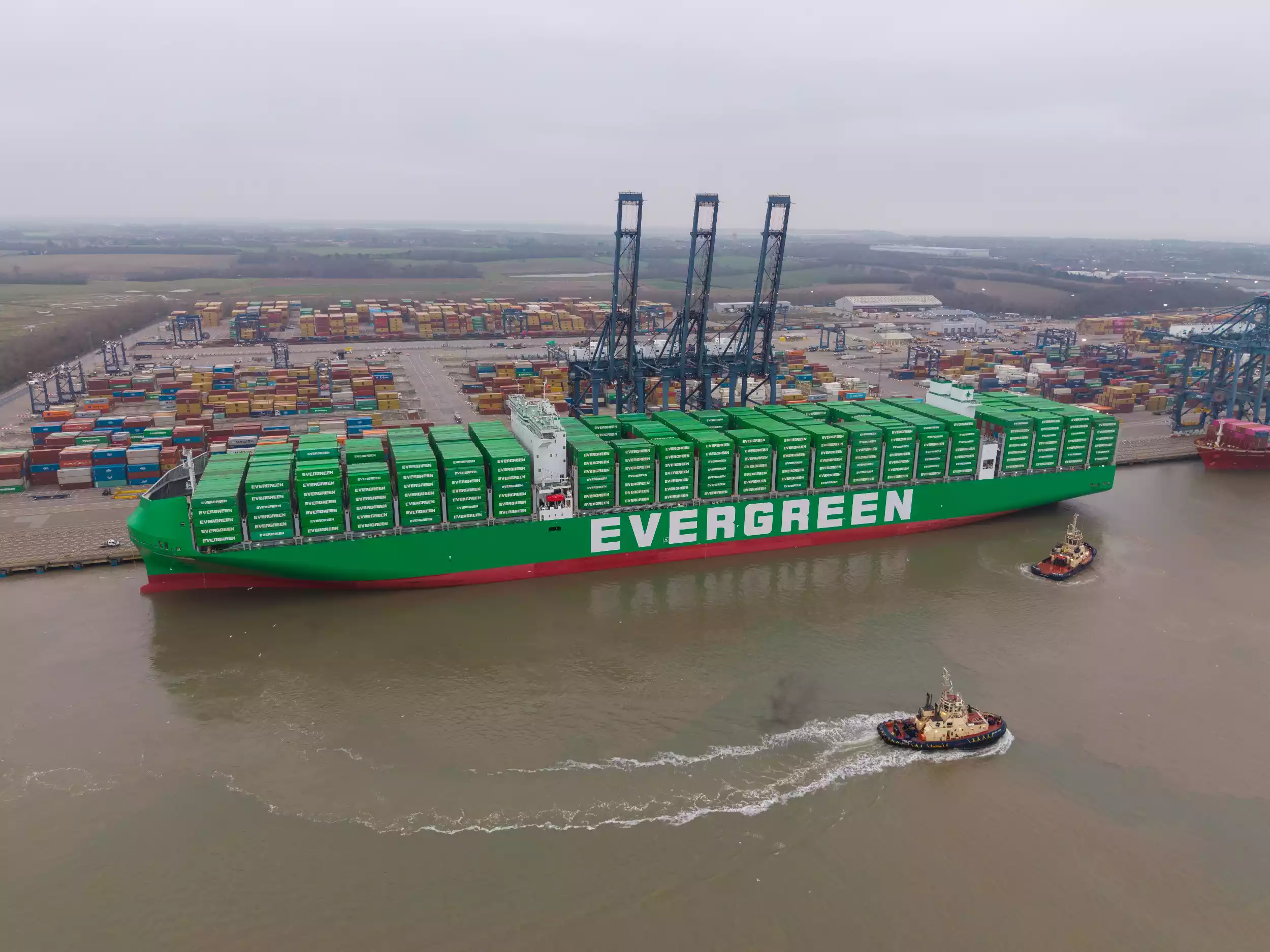 Aerial view of Ever Eco manoeuvring in Felixstowe harbour at dusk with tugboat alongside