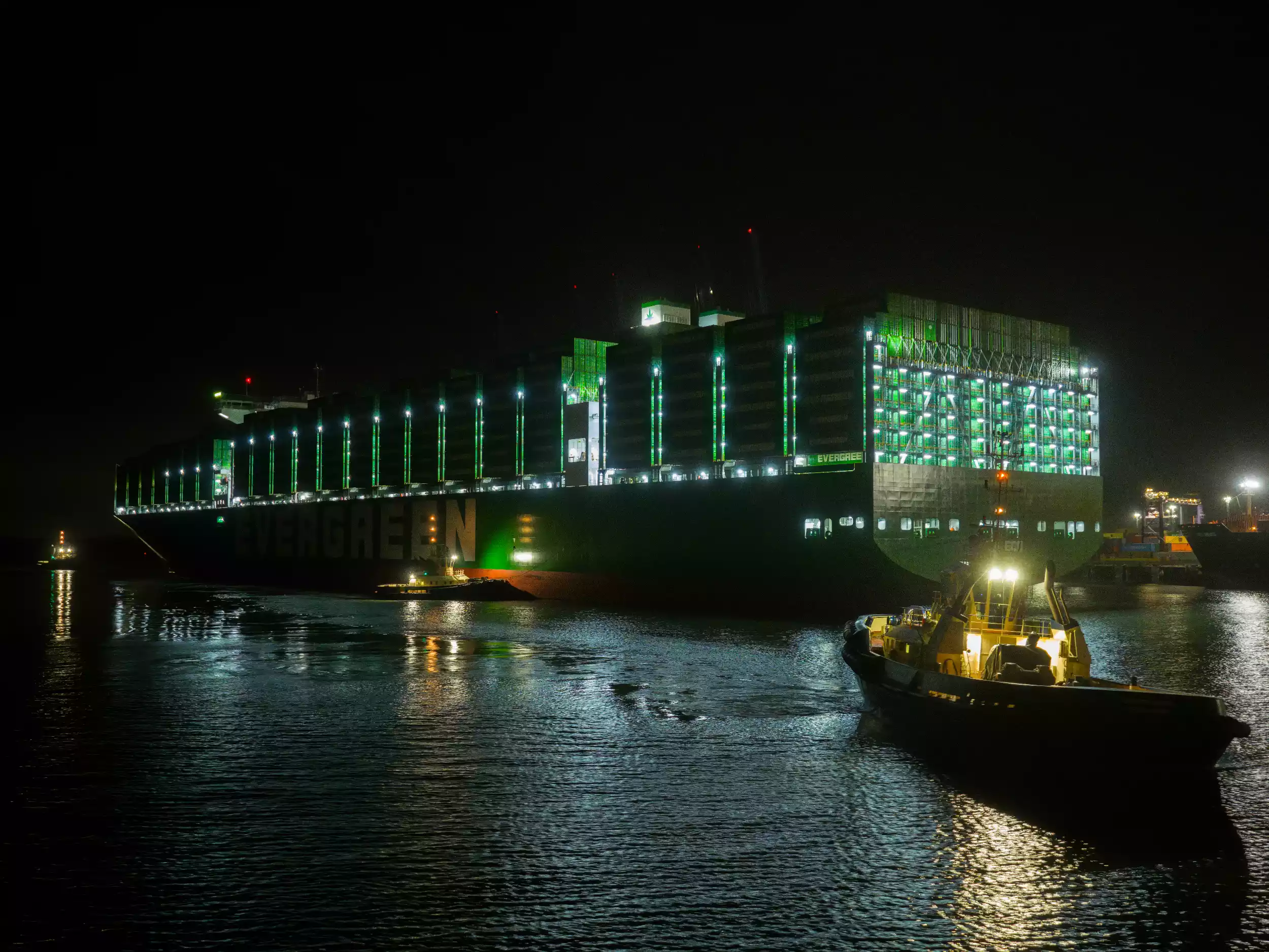 Wide aerial of Ever Eco illuminated at Felixstowe terminal during evening operations