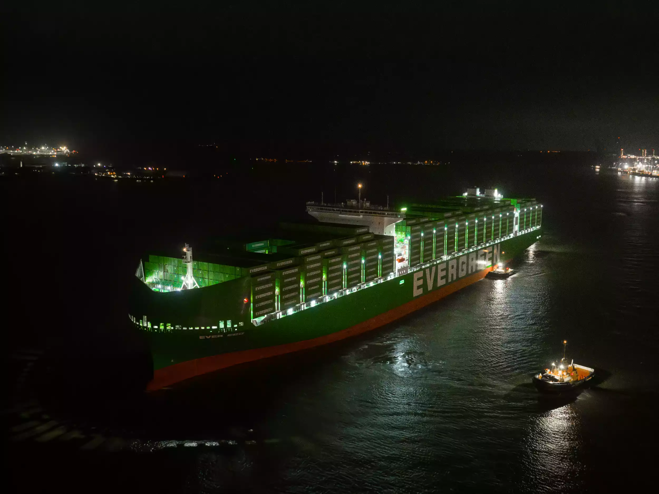 Aerial view of Ever Eco departing Felixstowe lit by port lights in near darkness