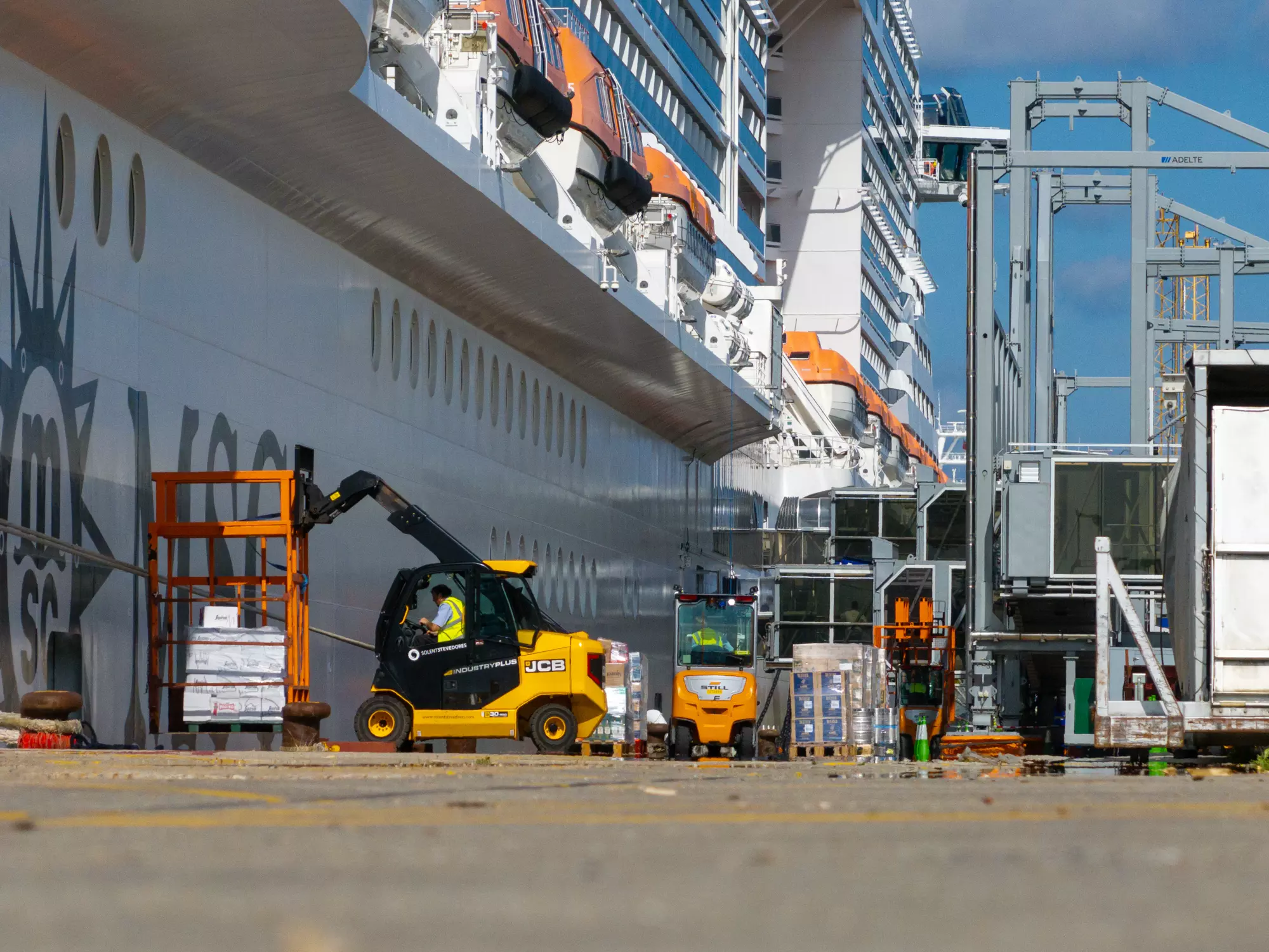 Forklifts and port vehicles working alongside a cruise ship on the Southampton quayside