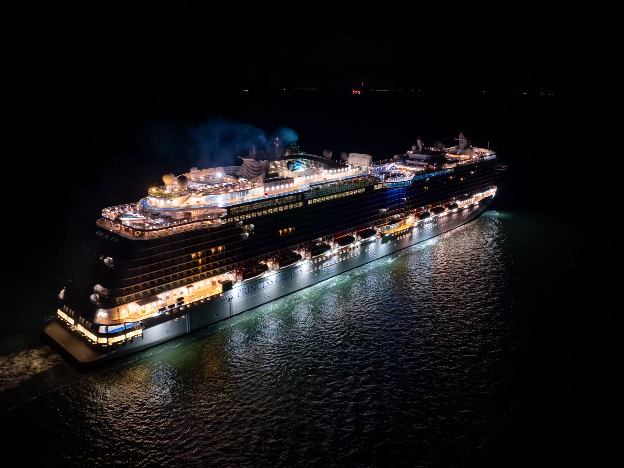 Cruise ship lit up at night departing Southampton, aerial drone photo