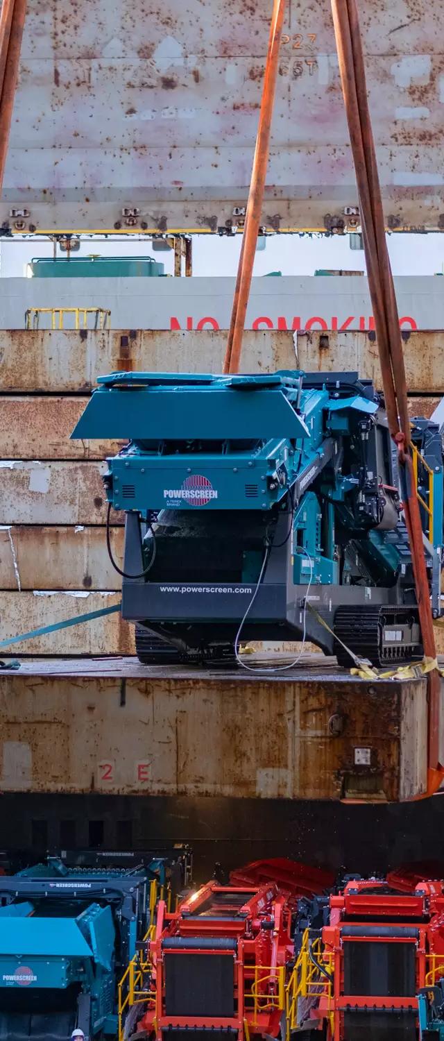 Terex machine lifted by crane into the ship's hold above rows of plant already loaded for DHL Industrial Projects